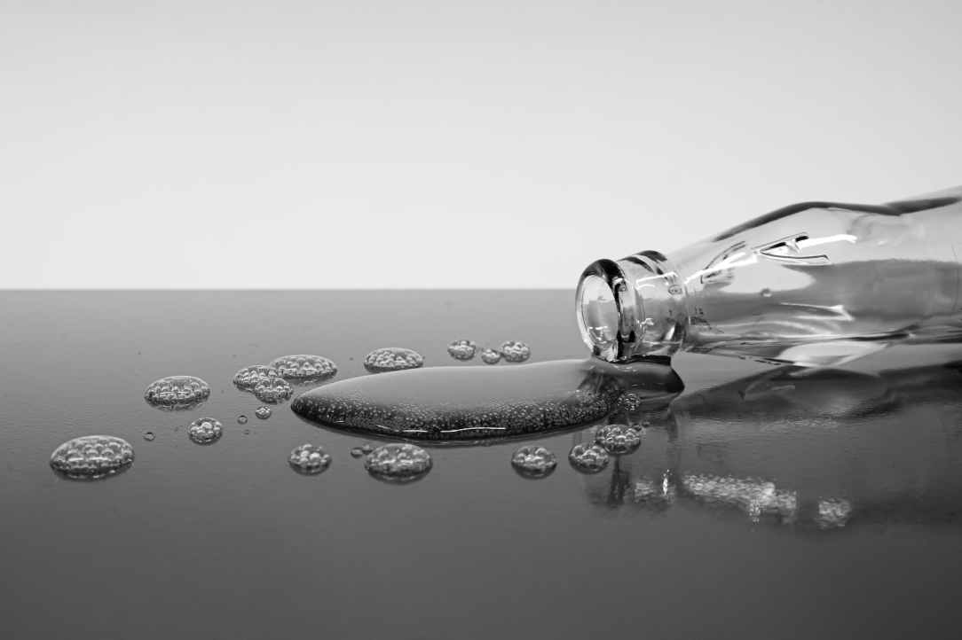 a glass bottle lying on its side with spilled water